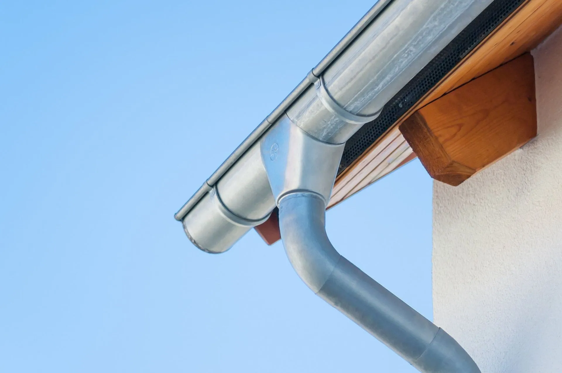 Metal gutter and downspout on the corner of a house.