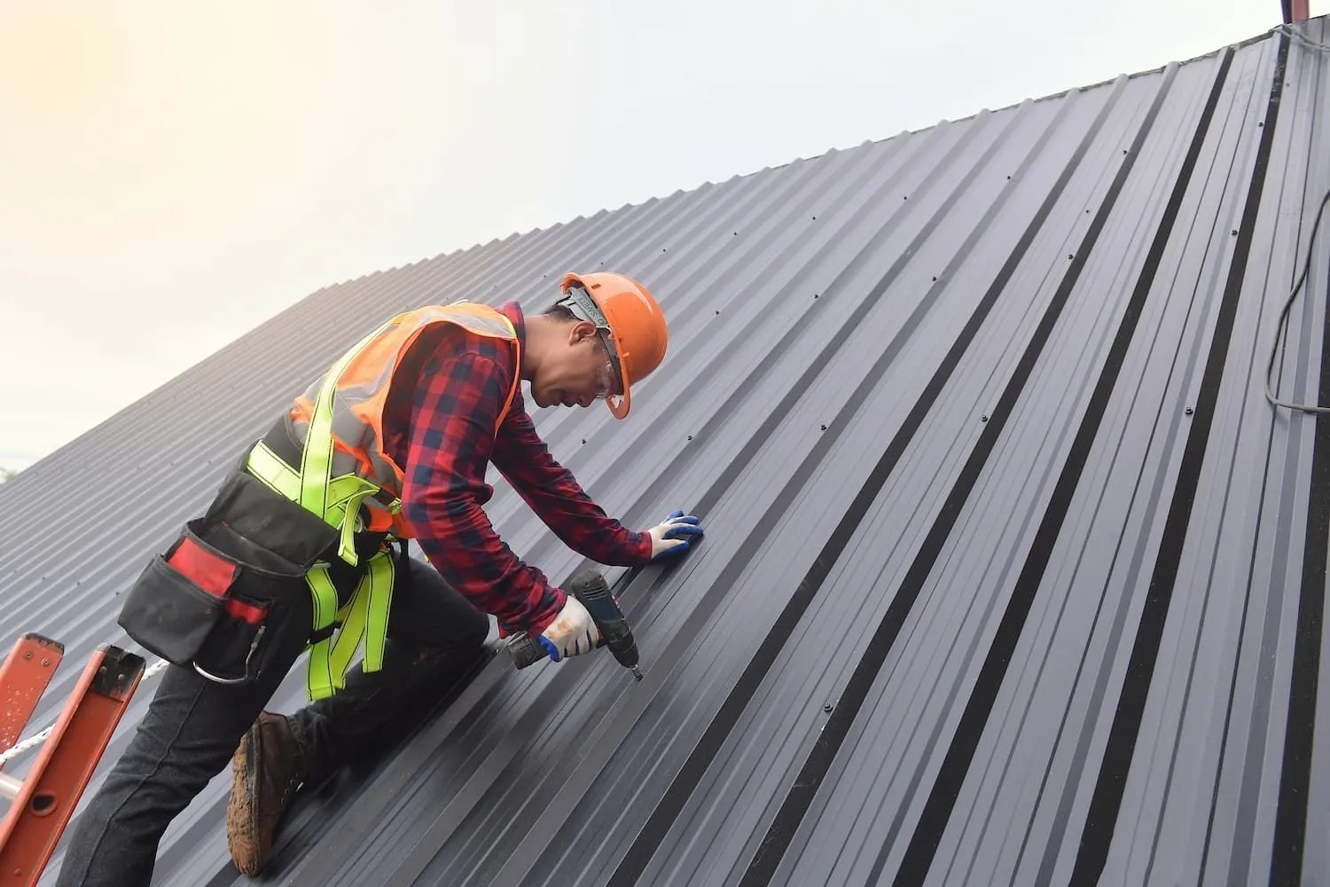 Metal roofing contractor in safety gear working on a residential roof.