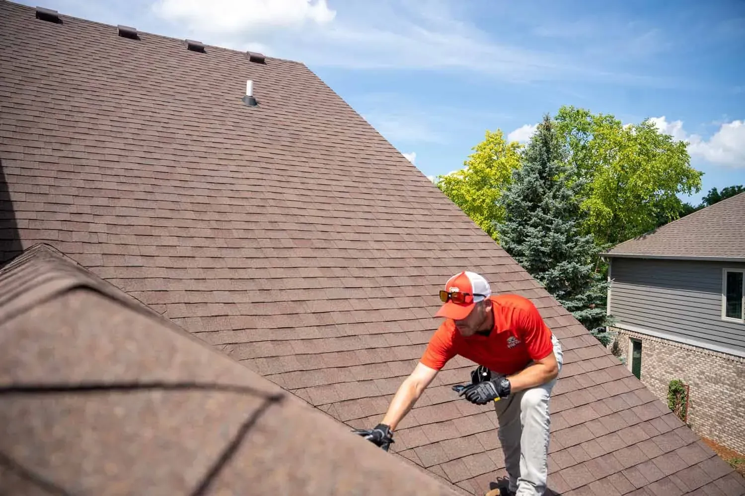 Roofer inspecting and repairing an asphalt shingle roof.